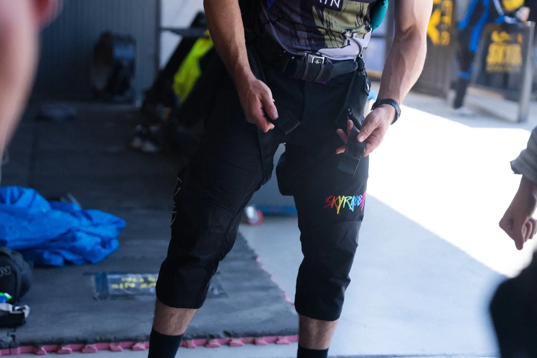 Skydiver adjusting a harness over Skyrabbit shorts at the drop zone